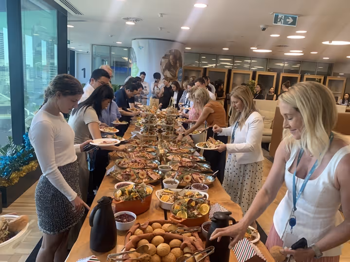 People serving themselves from a buffet table with assorted dishes in a bright room.