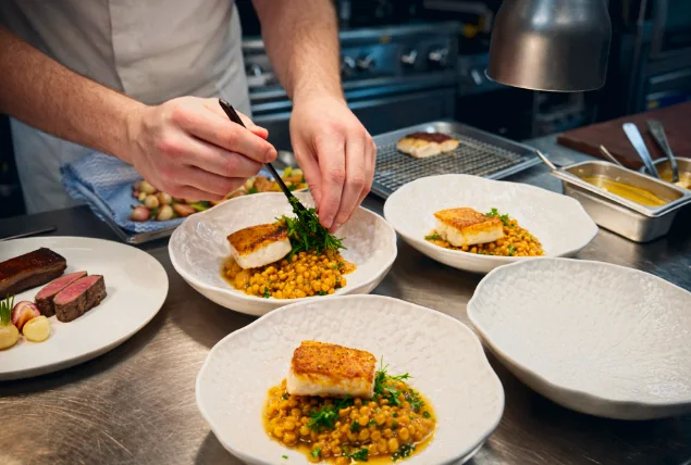Chef finishing plates of fish on lentils