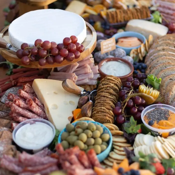 Cheese and meat platter with grapes, olives and dips.