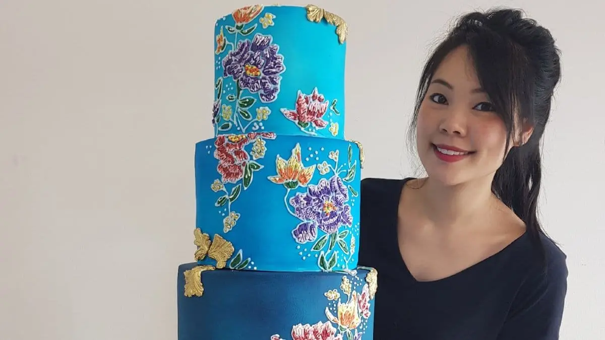 Amanda Chow from Sutsa with an elaborately decorated blue cake with flowers.