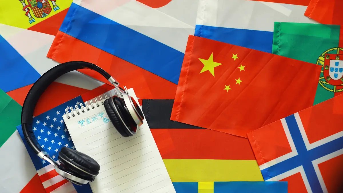 Various international flags with headphones and a notebook to learn a language.