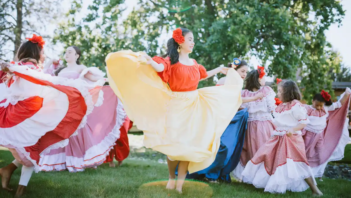 Group of women dancing outside in traditional dresses.