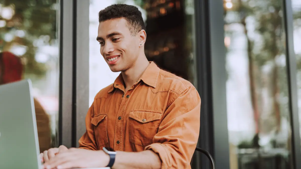 Man working on a computer wearing an orange shirt.