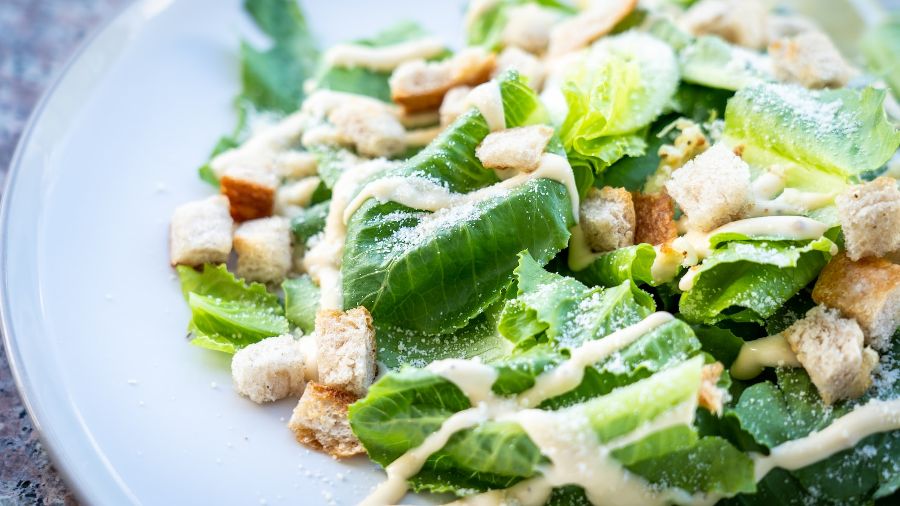 A white plate with a Caesar salad on it
