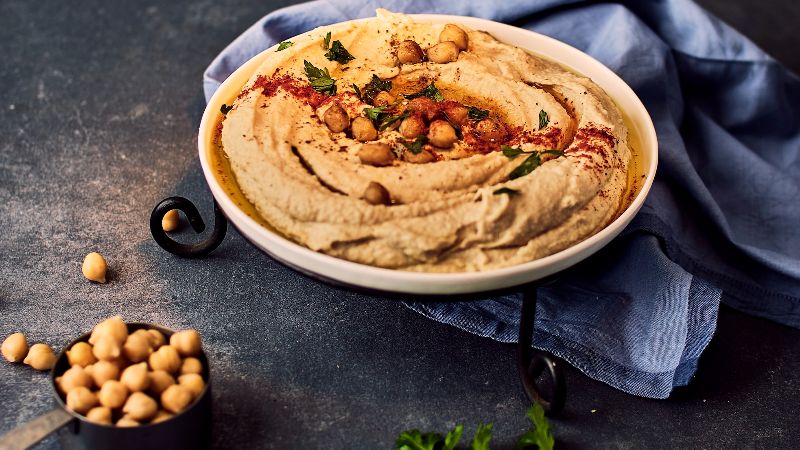 A bowl of hummus and a cup of chickpeas.