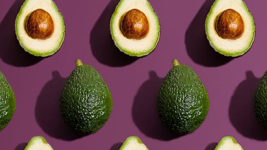 Cross sections of avocados on a purple backdrop