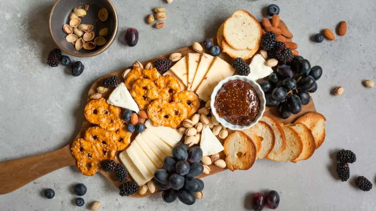 Wooden board with cheese, biscuits and fruit.