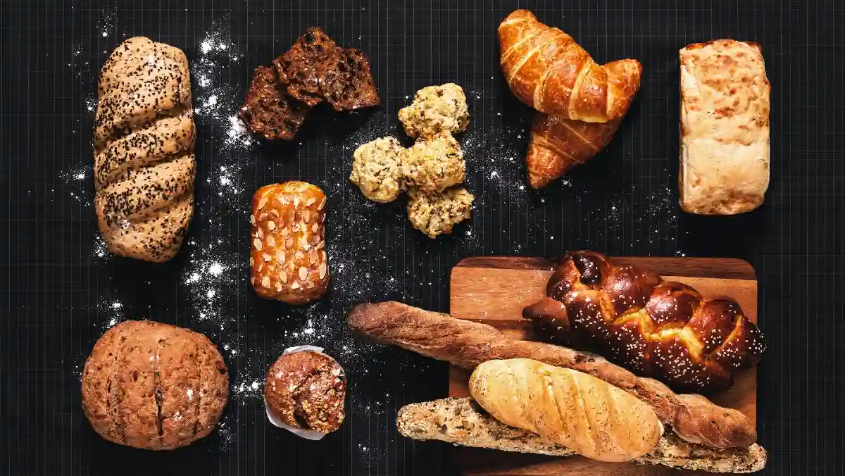 Range of pastries, including loafs, croissants and brioche, on a black table.