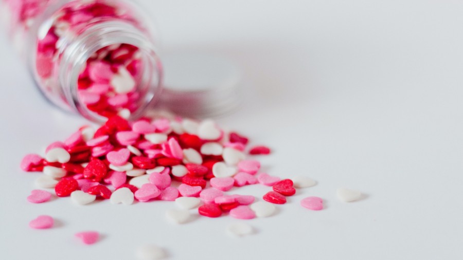 A jar of red, pink and white candy hearts spilling over