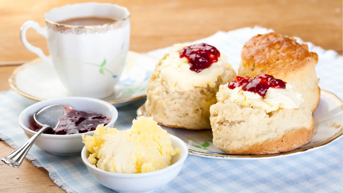 A traditional Devonshire tea with scones, jam, cream and a milk tea.