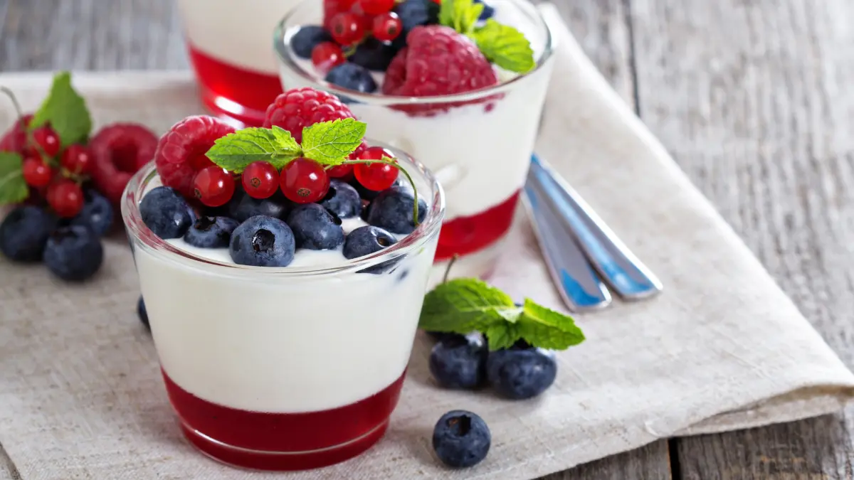 Two glass cups with yogurt topped with berries.