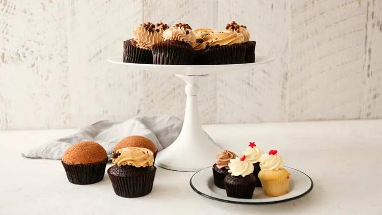 Cake stand with chocolate cupcakes and a plate with more cupcakes.