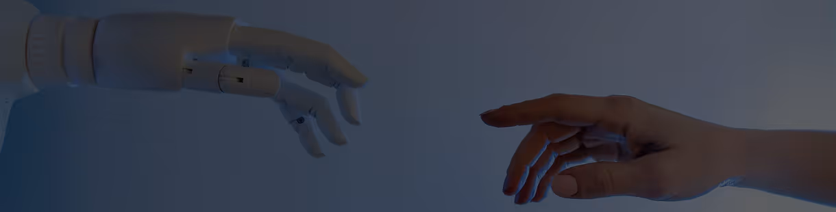 Robotic hand reaching out to touch a human hand against a dark background.