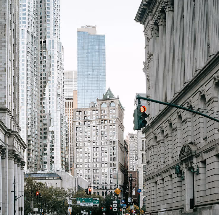 Urban street scene with historic and modern buildings, traffic lights, and street signs in a city.