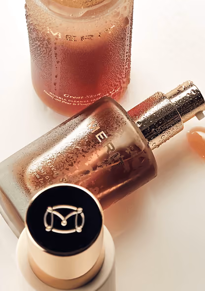 Three cosmetics bottles with condensation, one lying down with a pump dispenser and a black cap visible.