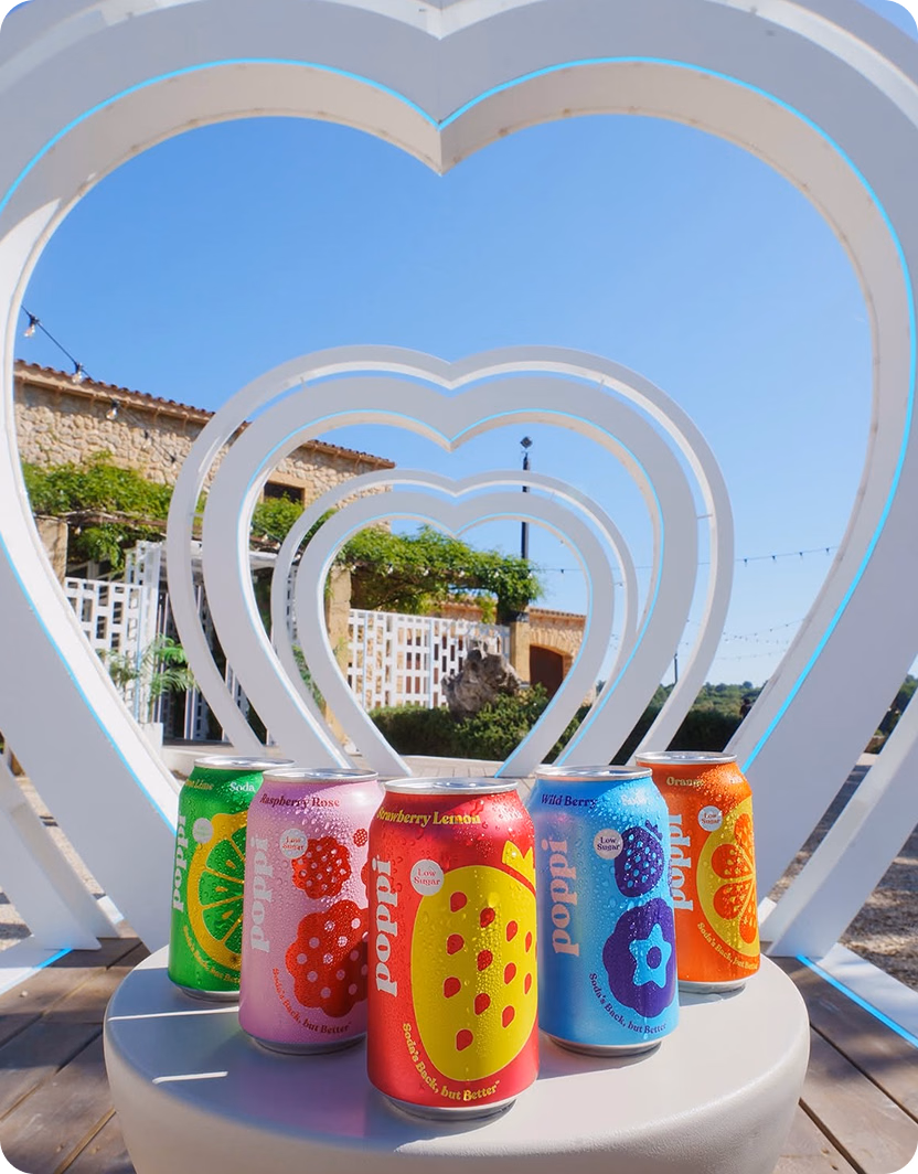 Poppi cans in front of a white heart-shaped arch installation