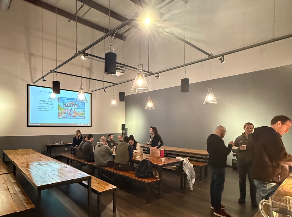 A group meeting in and around tables with a screen projection