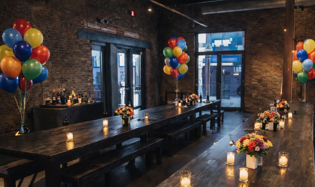 Long wooden table decorated with balloons, flowers and candles.
