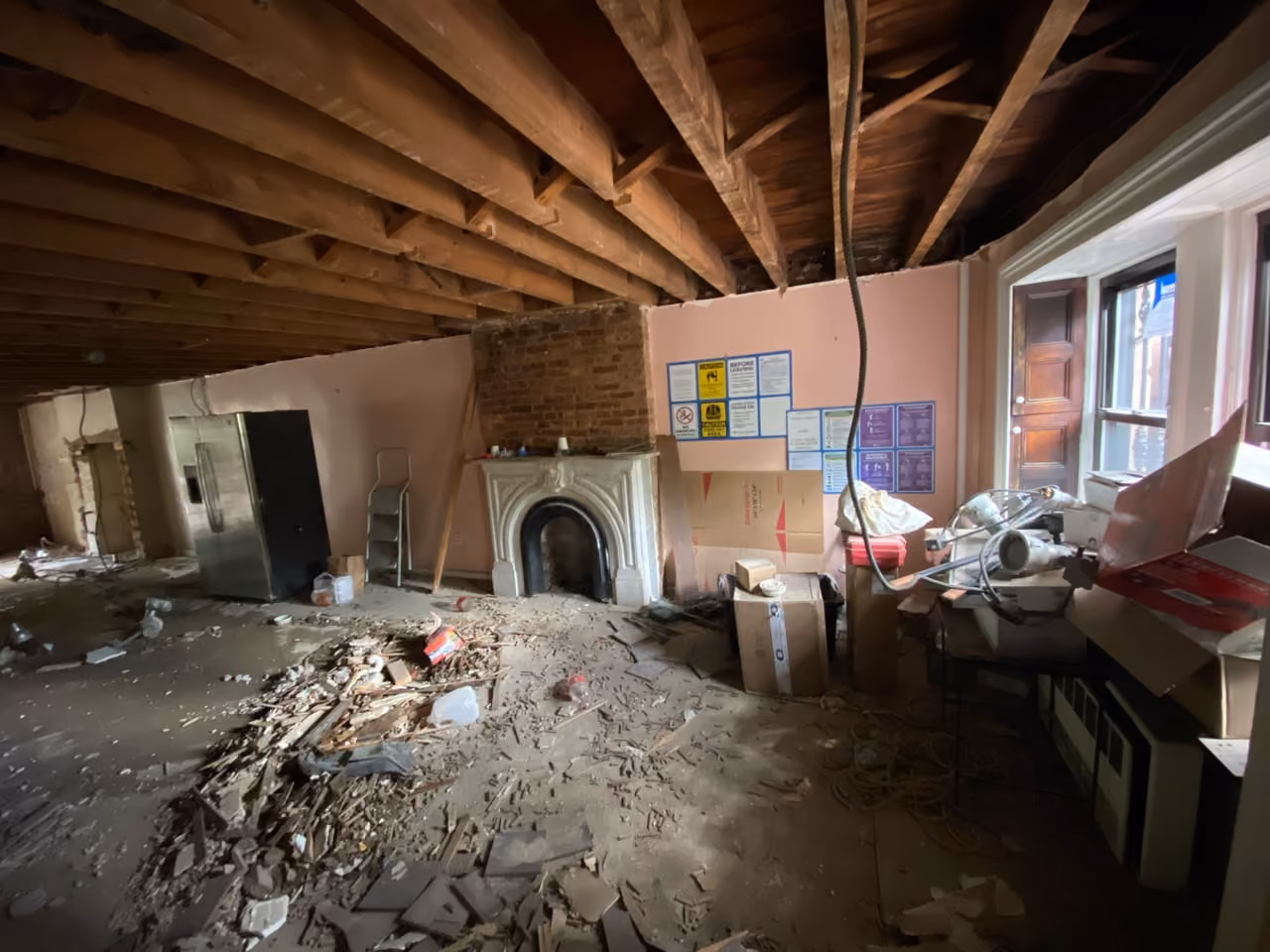 Demolition of the parlor floor with exposed brick and original fireplace during a gut renovation of a Carroll Gardens brownstone at 347 President Street, Brooklyn, by Gallery KBNY