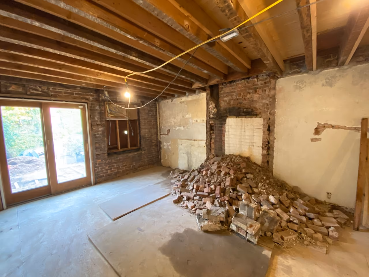 Gutted rear room with exposed joists and garden doors during a Carroll Gardens brownstone renovation at 347 President Street, Brooklyn, by Gallery KBNY
