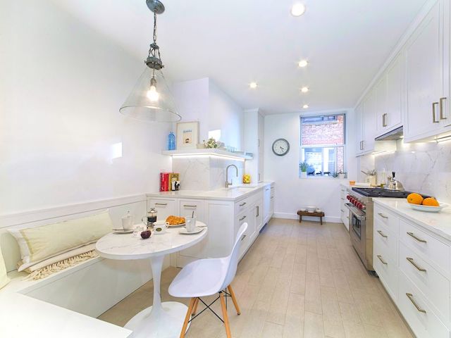 Galley kitchen with white shaker cabinets, built-in banquette and round marble table in a pre-war co-op at 895 West End Avenue by Gallery KBNY