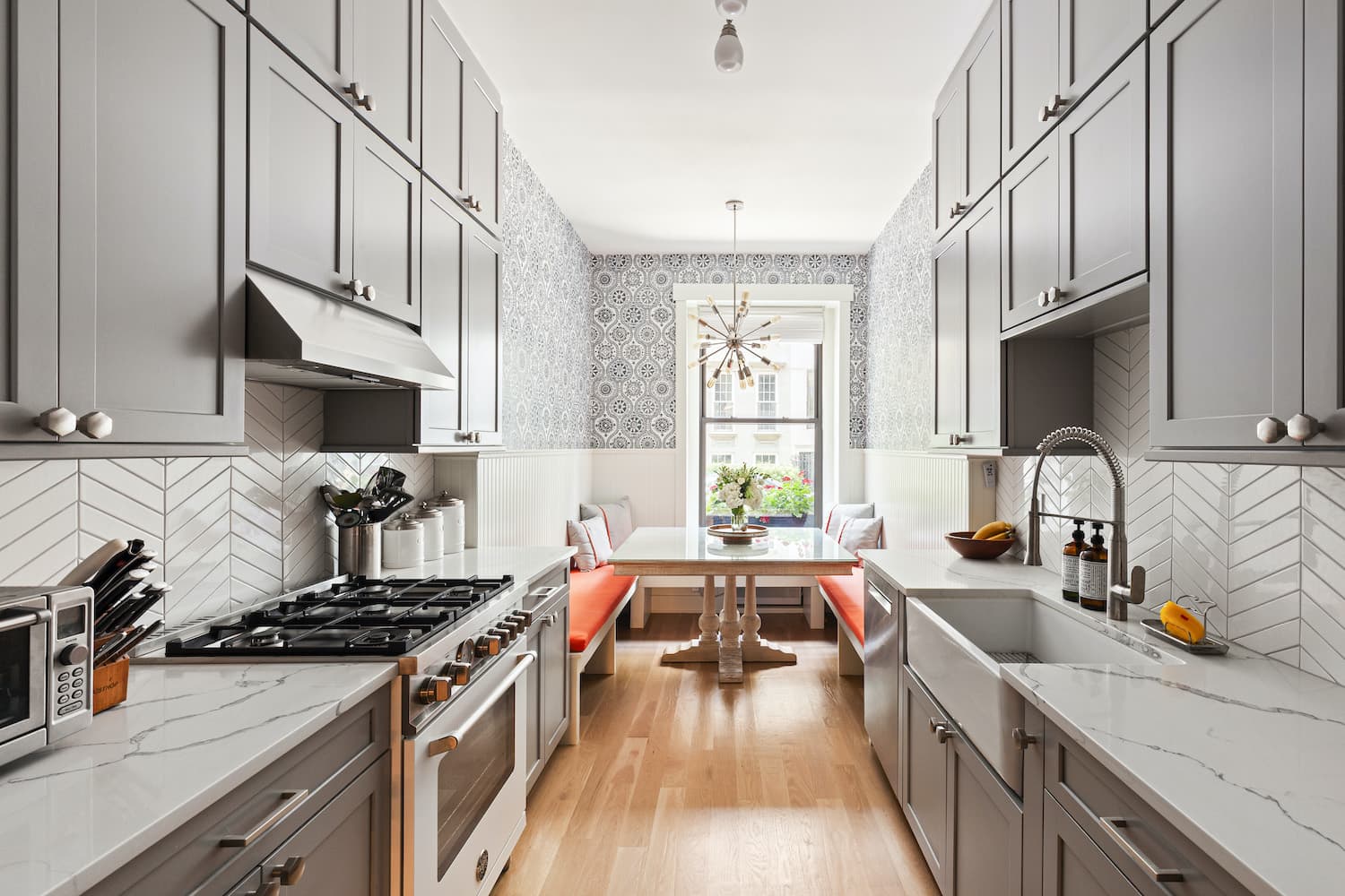 Townhouse galley kitchen with gray cabinets, chevron tile and orange banquette at 529 East 87th Street by Gallery KBNY
