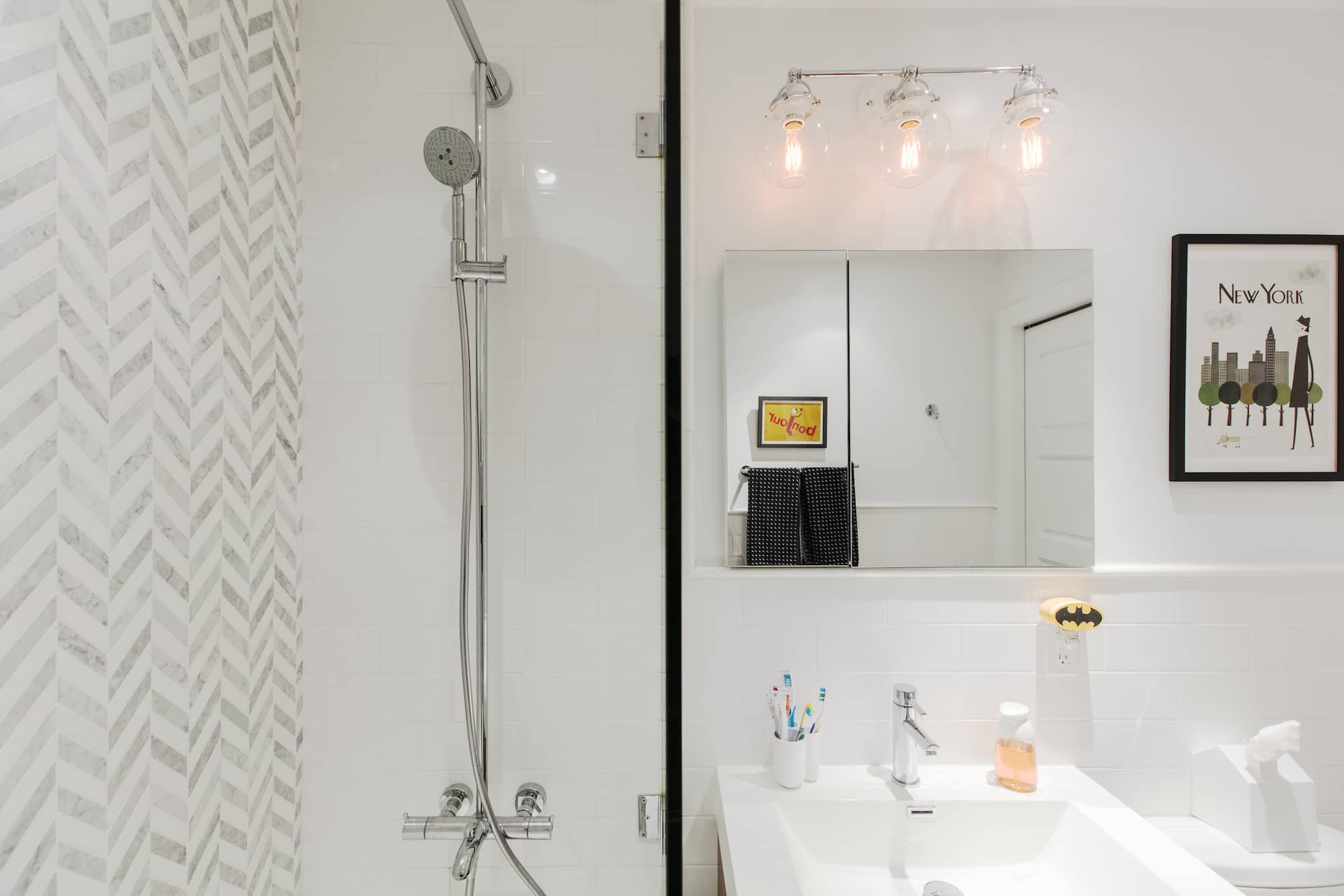 Bathroom shower with marble herringbone tile, chrome fixtures and a vanity mirror in a pre-war Carroll Gardens condo by Gallery KBNY