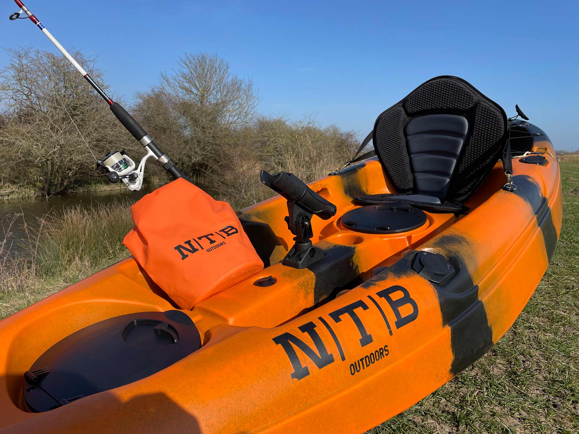 An orange NTB kayak on a grass verge