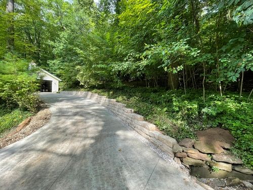 Strong concrete block retaining wall with integrated flower beds and proper drainage.