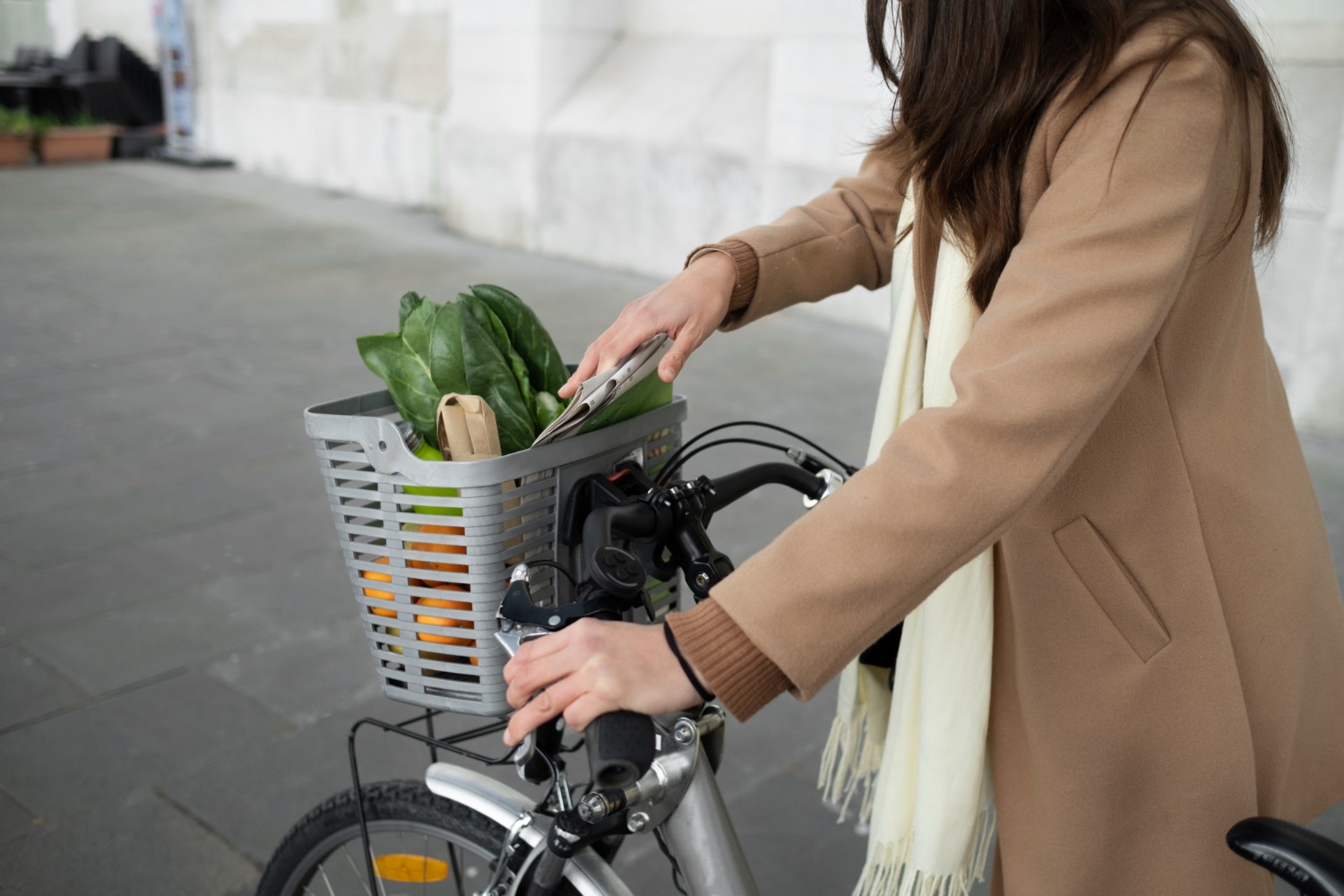 Lady with brown hair on bike with basket filled with vegetables