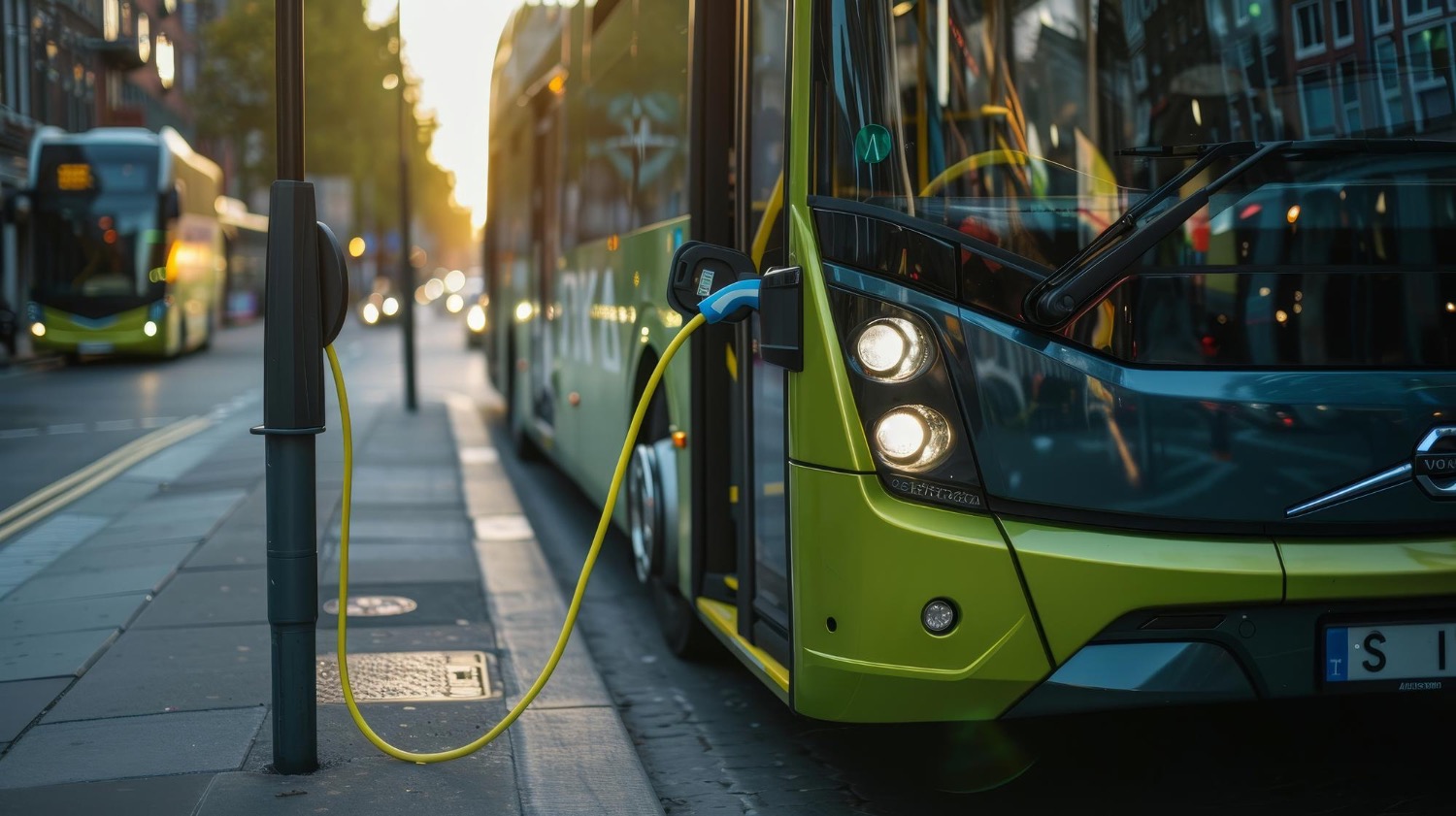 Electric green bus on street plugged into electric charger