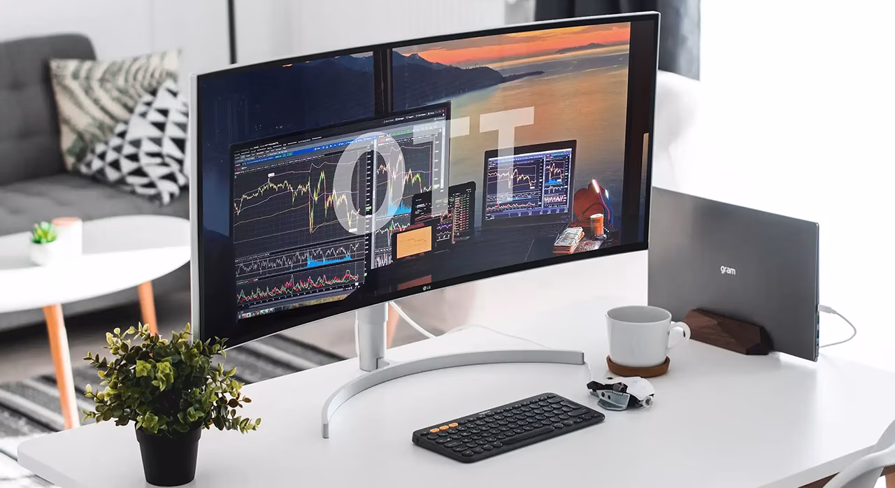 A monitor on a white table showing financial graphs and big OTT sign on the screen