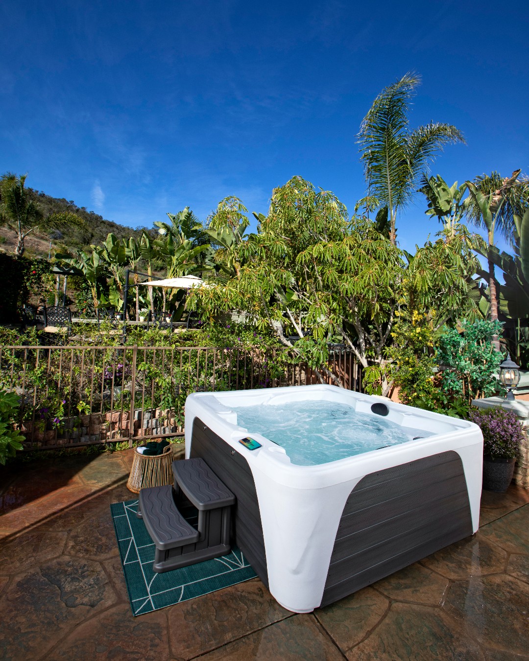 Witte jacuzzi op stenen terras met palmbomen en blauwe lucht