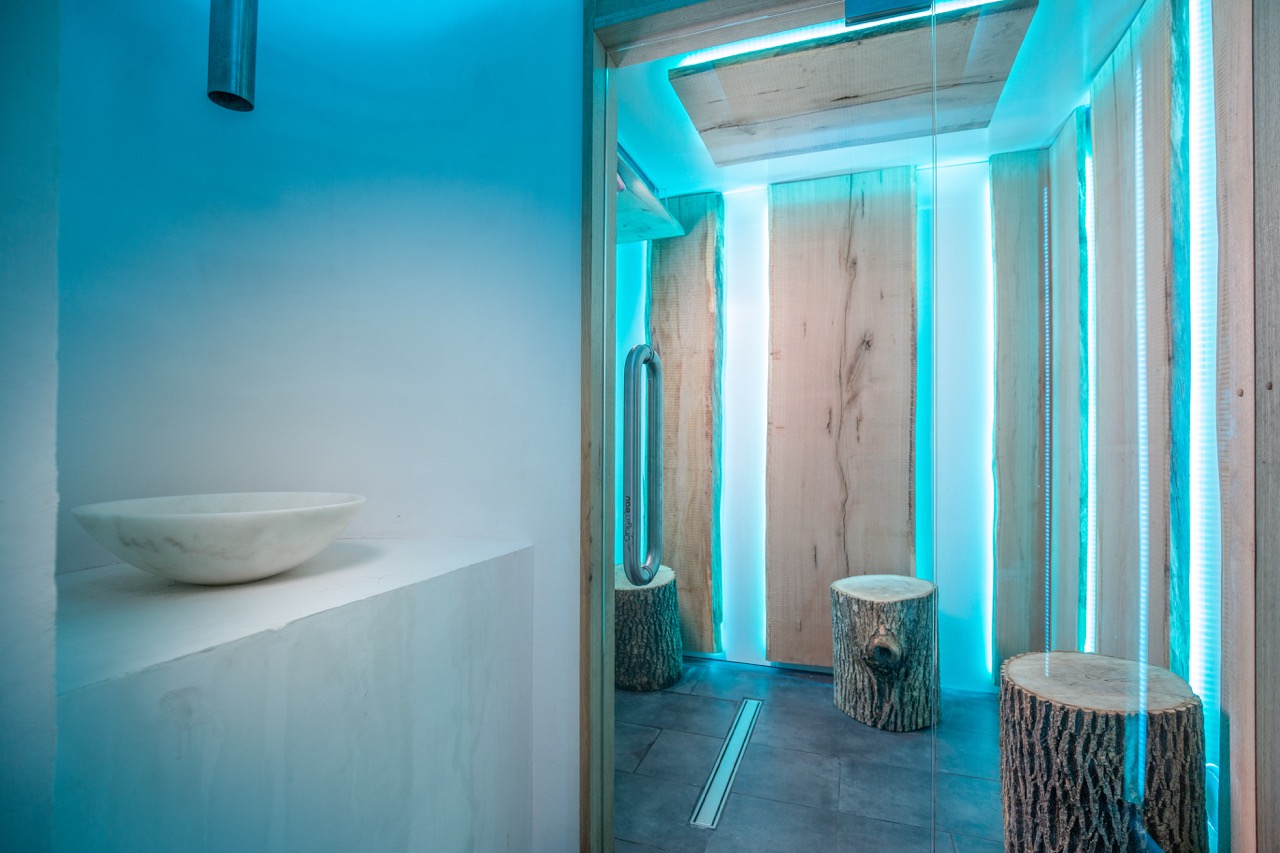 Moderne badkamer met blauwe verlichting en boomstronk krukken