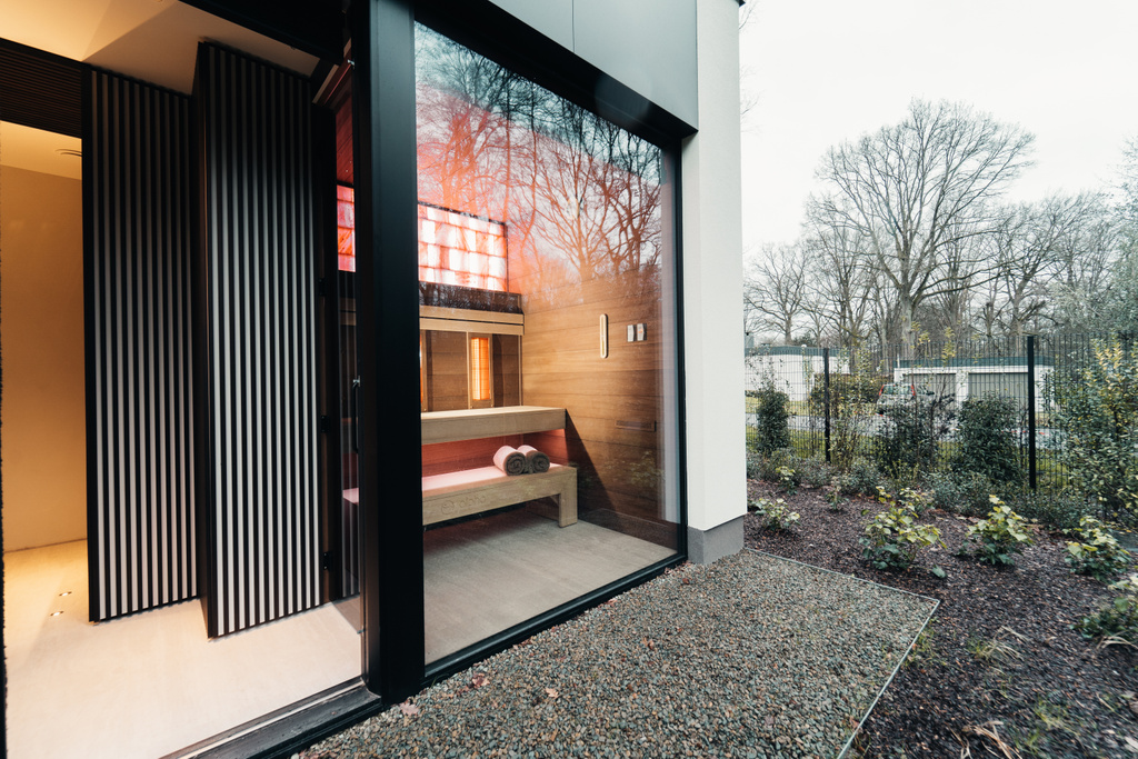 Moderne sauna met groot raam, uitzicht op winterse tuin met naakte bomen