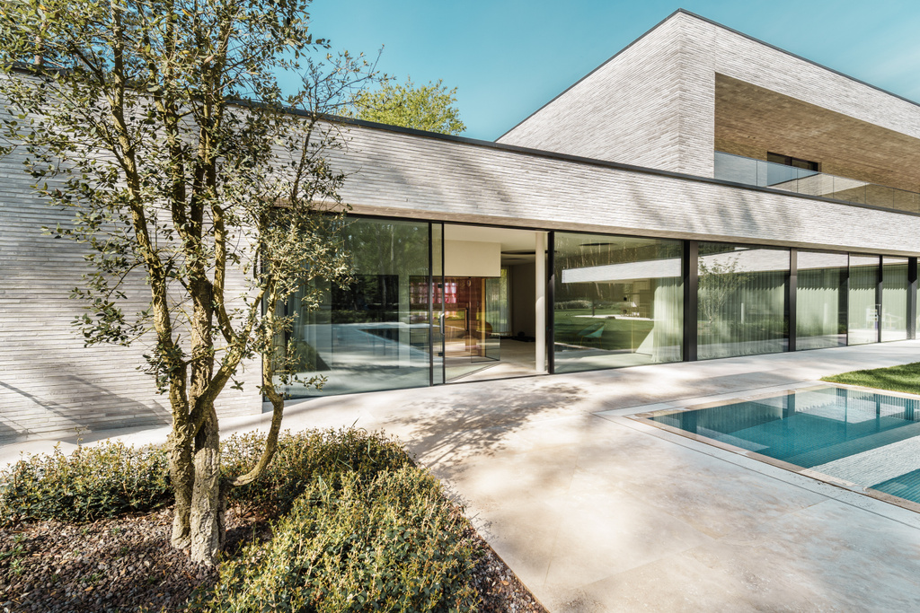 Moderne witte villa met zwembad en grote ramen tussen groene bomen
