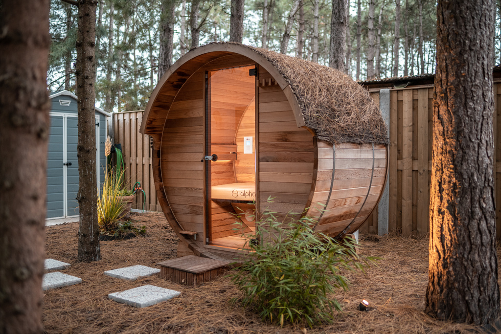 Houten barrel sauna in bosrijke omgeving met openslaande deur