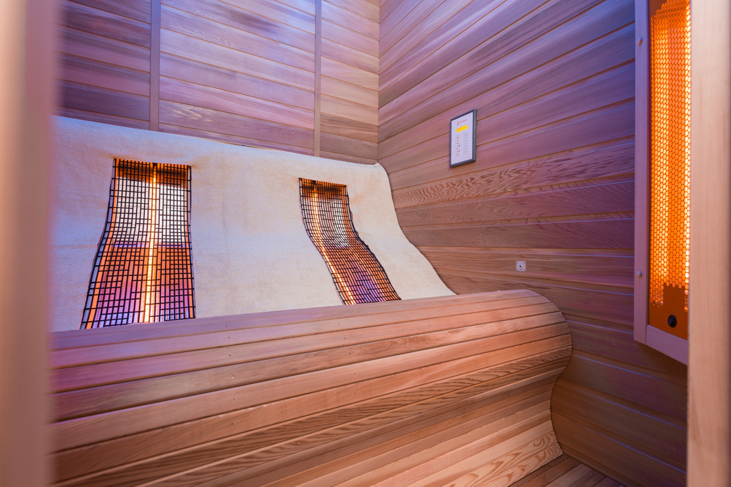 Moderne houten sauna met golvende bank en oranje verwarmingselementen