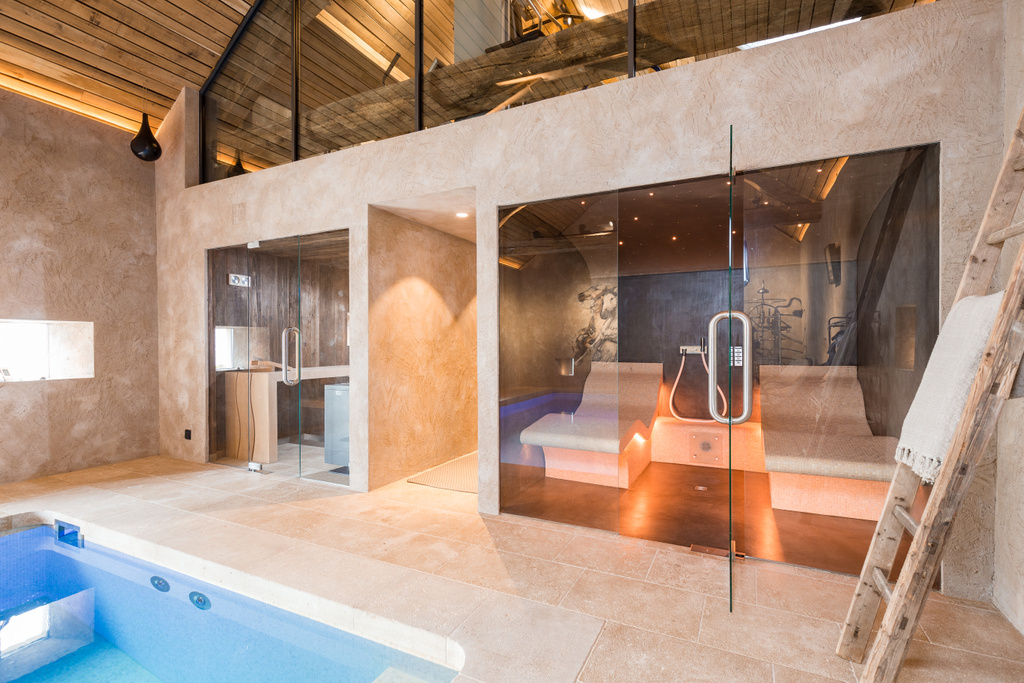 Moderne wellnessruimte met blauwe jacuzzi en glazen sauna