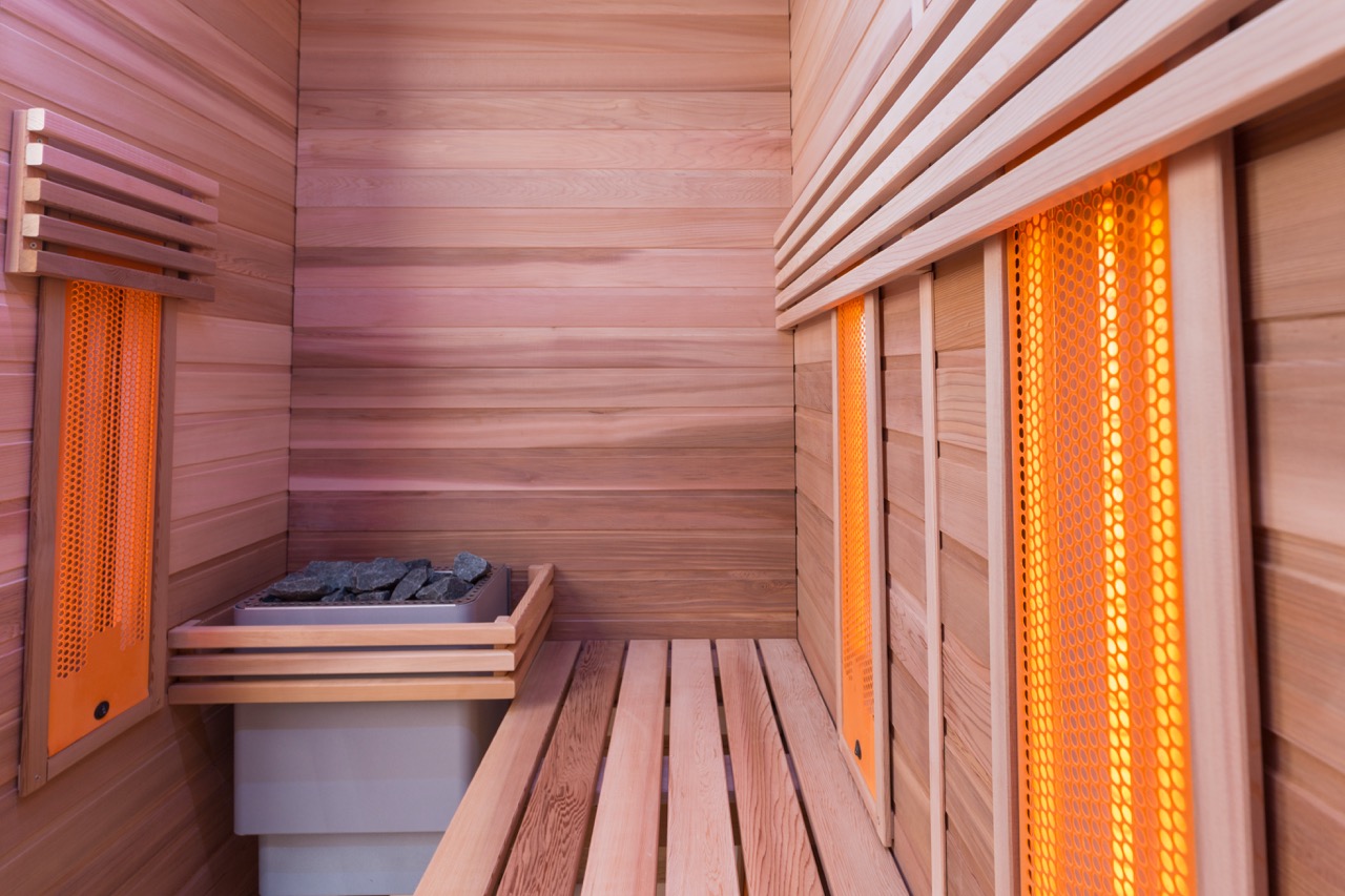 Moderne houten sauna met oranje gloeiende verwarming en steenoven
