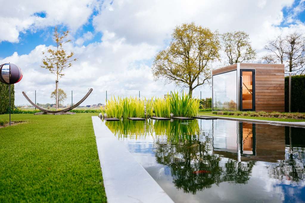 Moderne tuin met vijver, weerspiegeling, groene gazons en houten tuinhuis