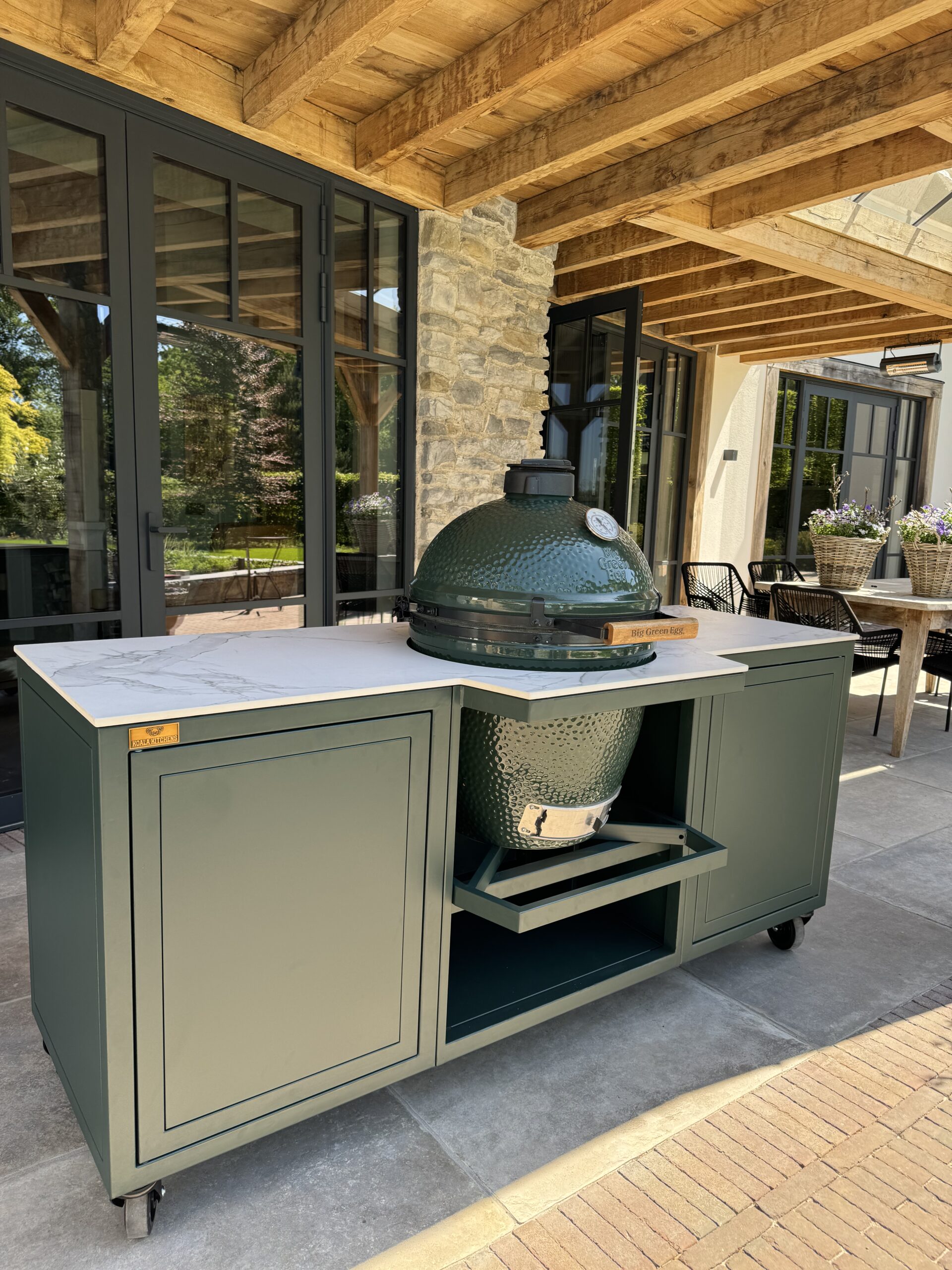 Groene Big Green Egg op een stijlvol terras met houten balken