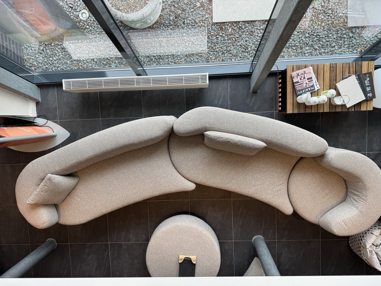 Design zitbank in grijze ruimte met groot raam en houten accessoires