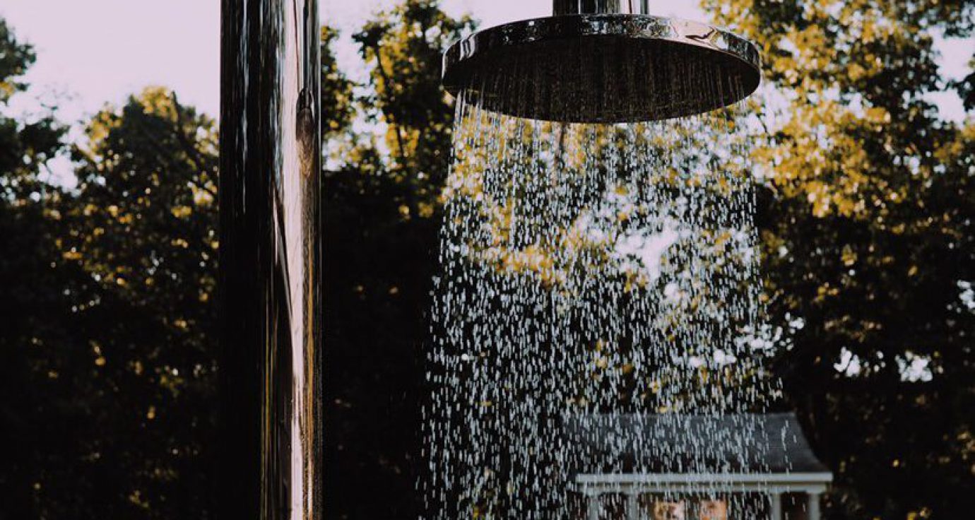 Buitendouche met vallend water en gele herfstbladeren op de achtergrond