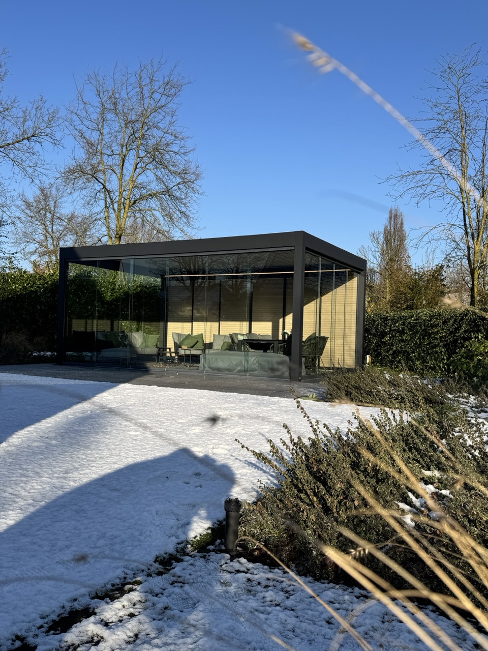 Moderne Renson-terrasoverkapping met glazen wanden in besneeuwde wintertuin