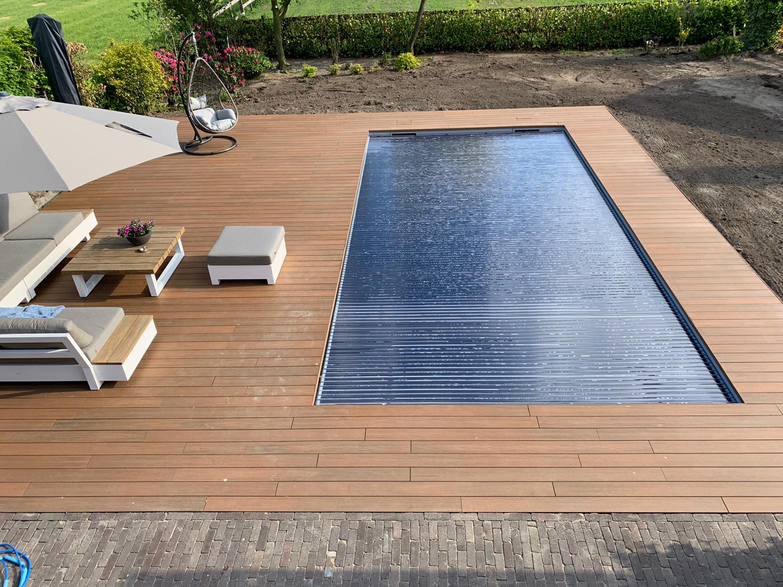 Luxe buitenzwembad met houten terras en relaxzone in groene tuin