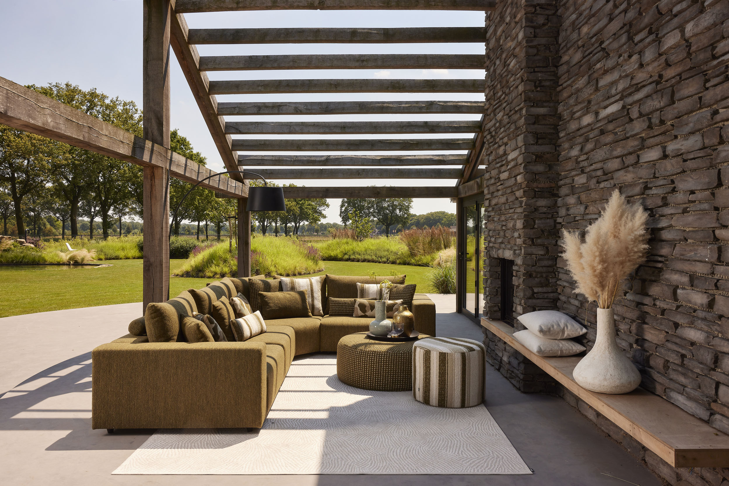 Modern overdekt terras met groene bank en uitzicht op tuin met bomen