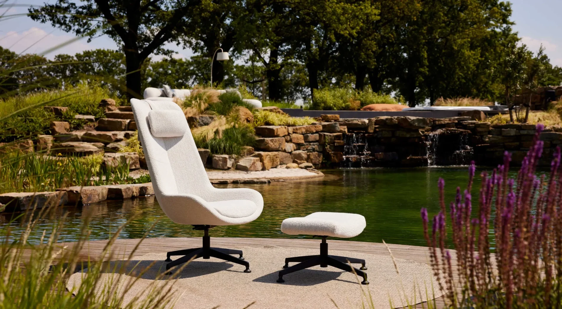 Witte fauteuil met voetenbank naast een rustieke watertuin met waterval