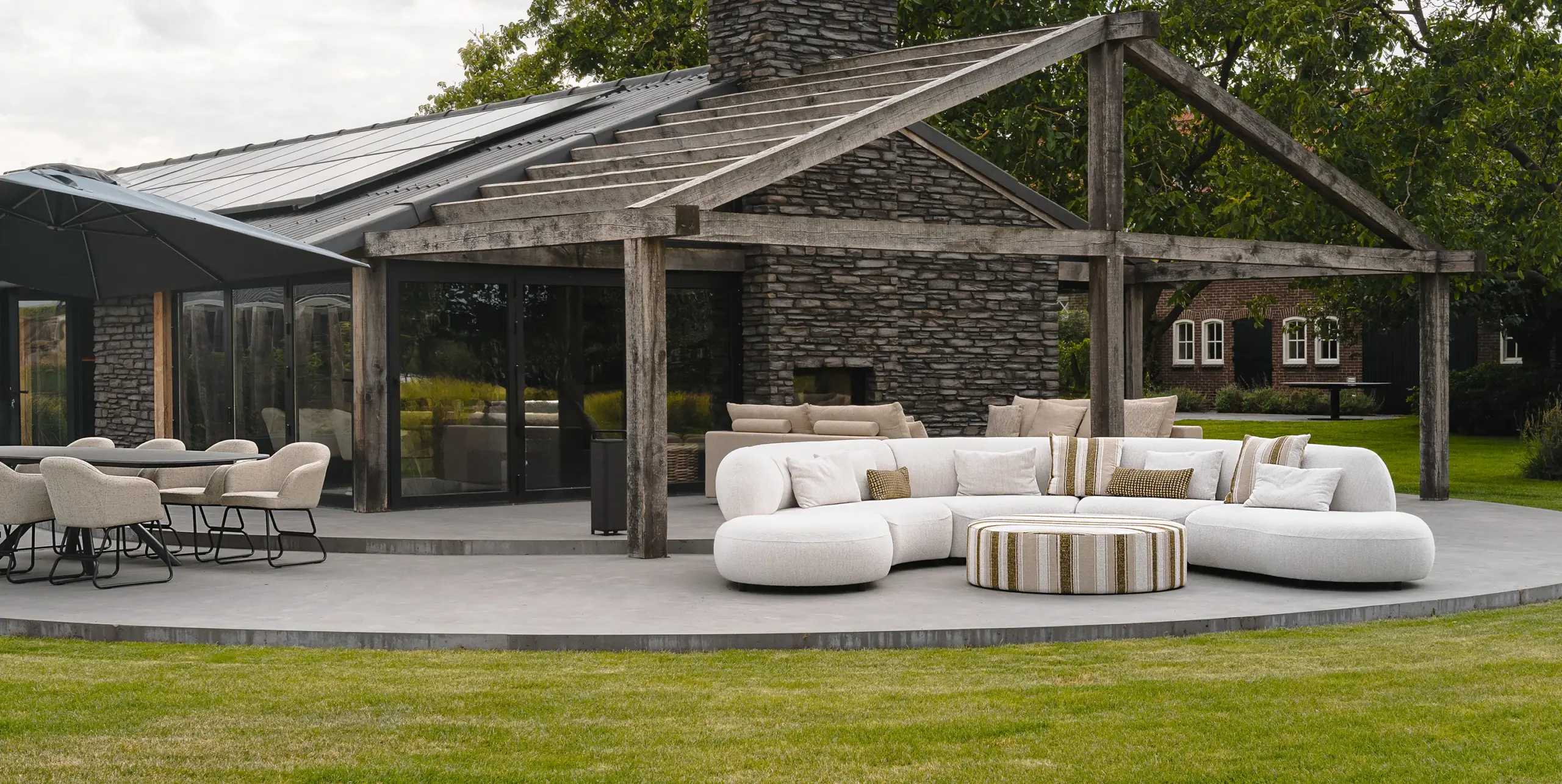 Moderne overdekte buitenruimte met stenen terrasoverkapping en wit meubilair