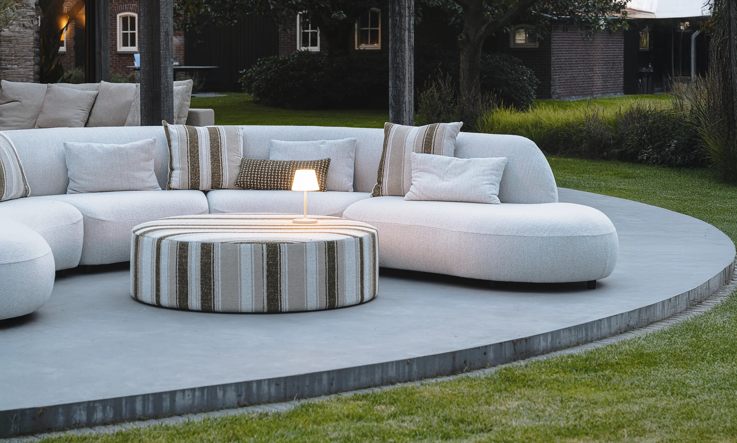 Moderne buitenruimte met witte bank, rond platform en gezellige verlichting